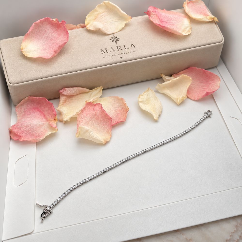 Silver 3mm moissanite tennis bracelet displayed with MARLA luxury jewellery packaging and delicate pink rose petals.