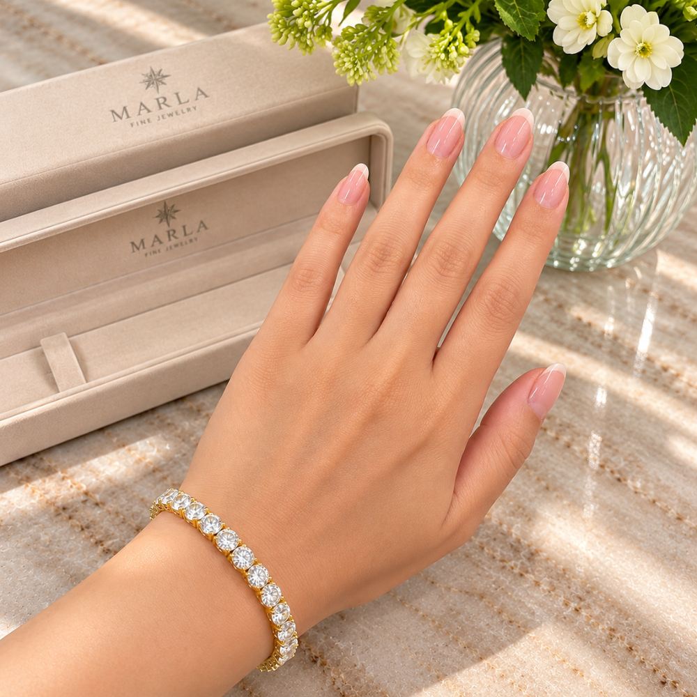 MARLA gold 4mm moissanite tennis bracelet featuring round brilliant-cut stones worn on a woman's wrist beside luxury packaging