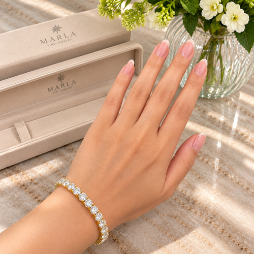 MARLA gold 4mm moissanite tennis bracelet featuring round brilliant-cut stones worn on a woman's wrist beside luxury packaging