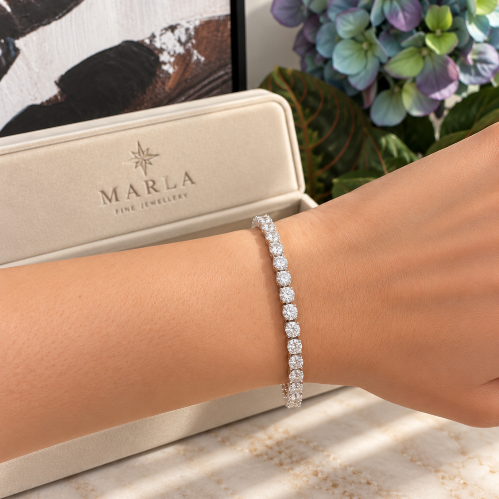 MARLA silver moissanite tennis bracelet featuring sparkling round-cut stones worn on a woman's wrist with luxury branded jewelry box