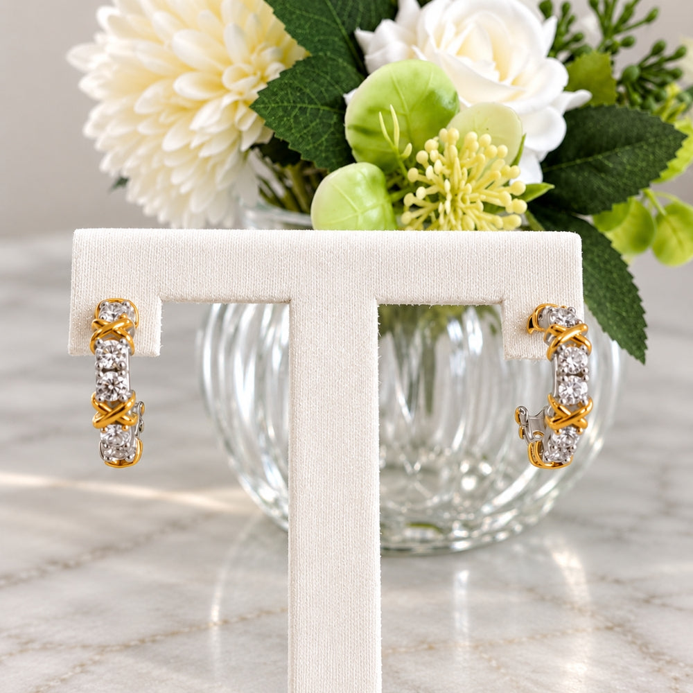 Celia Moissanite Hoop Earrings by MARLA Fine Jewellery displayed on a cream stand with white flowers, featuring brilliant stones and two-tone detailing.
