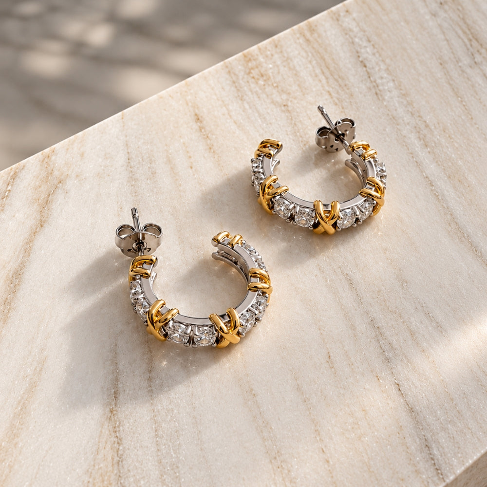 Pair of Celia Moissanite Hoop Earrings in 925 sterling silver with gold accents and sparkling round moissanite stones, photographed on cream marble.