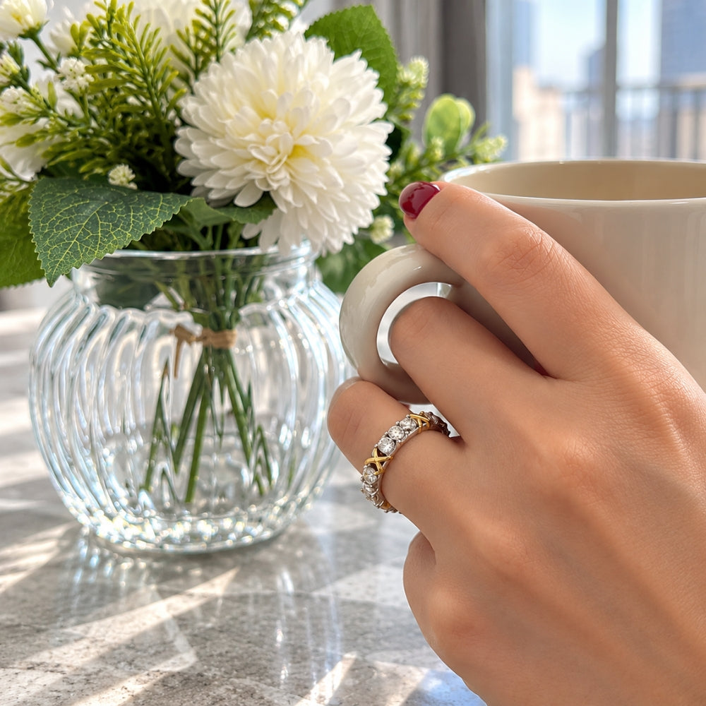 Woman wearing the MARLA Celia 1.5ct Moissanite Ring while holding a cream coffee cup beside elegant white flowers.
