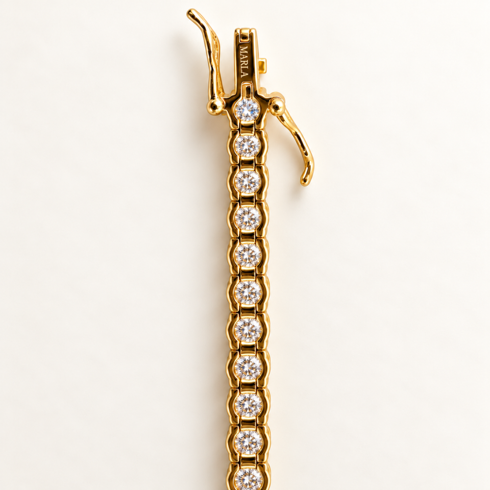 Close-up of MARLA gold tennis bracelet clasp featuring round brilliant-cut stones and engraved MARLA branding