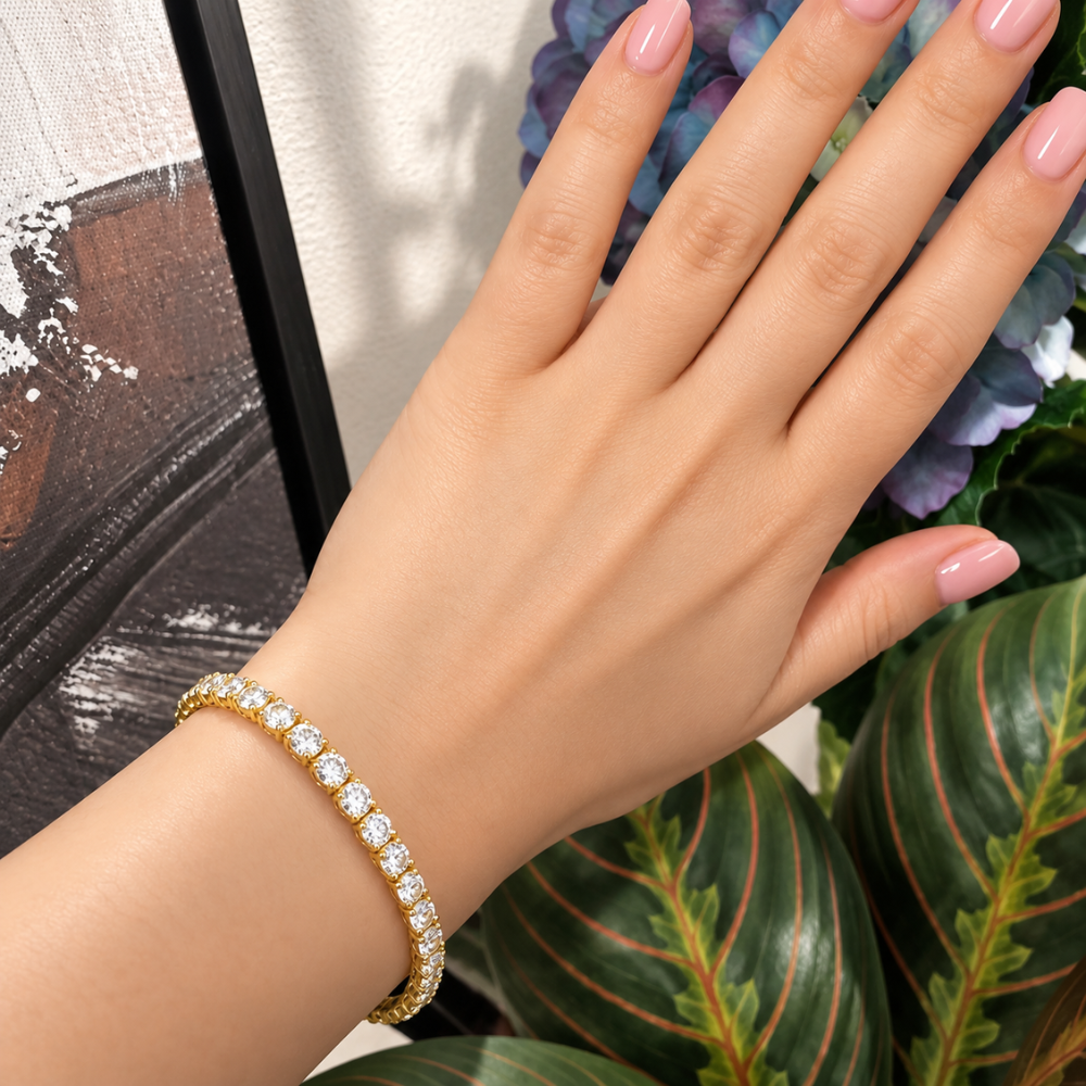 MARLA gold moissanite tennis bracelet with sparkling round-cut stones styled on a woman's wrist against botanical greenery