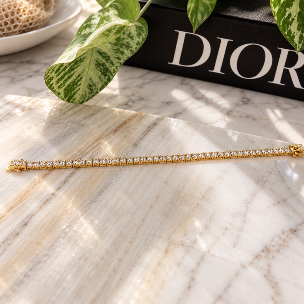 MARLA gold-tone moissanite tennis bracelet displayed on a luxury marble surface with soft natural lighting and elegant styling.