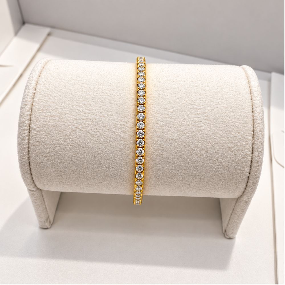 Gold 3mm moissanite tennis bracelet displayed on a cream velvet jewellery stand, showcasing its sparkling stone setting.