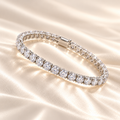 Marla Jewellery moissanite tennis bracelet featuring sparkling round-cut stones in a polished silver setting, elegantly displayed on luxurious champagne satin fabric.