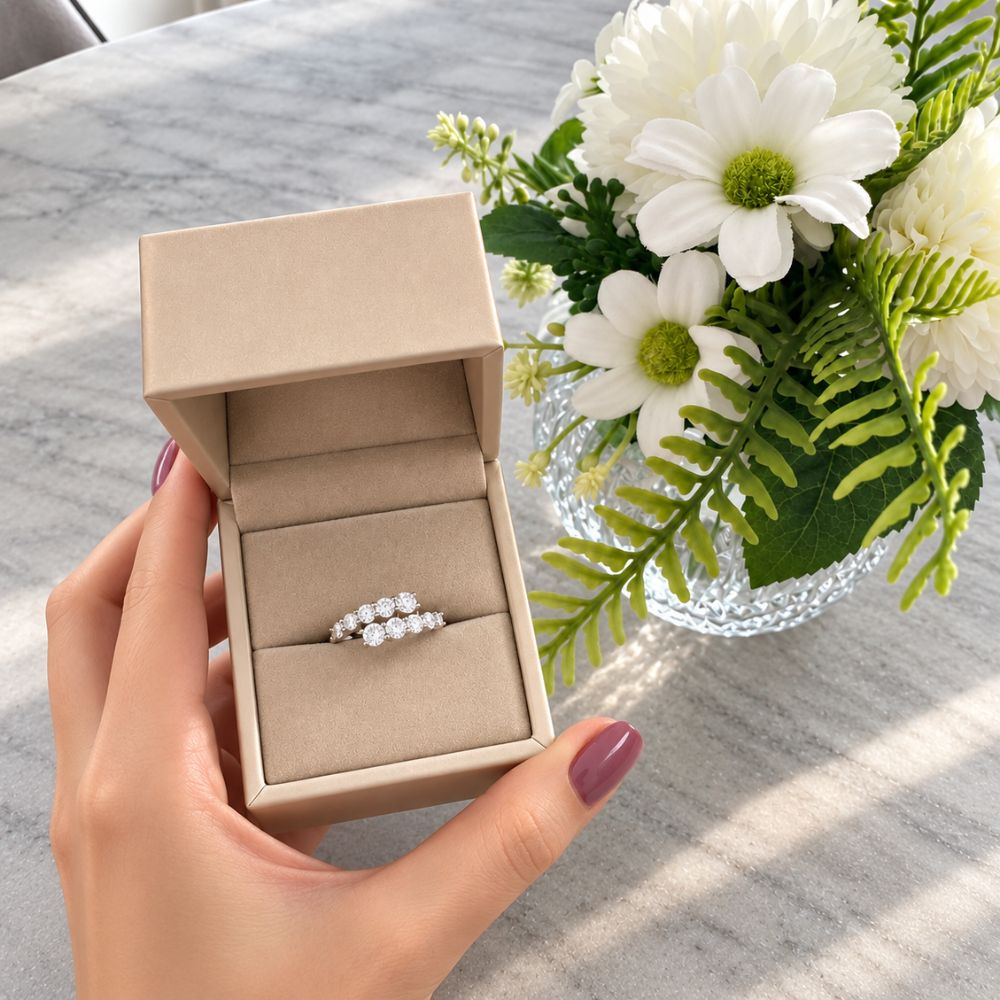Marla Jewellery double-row crystal ring presented in an elegant beige jewellery box, held by a manicured hand beside white flowers.