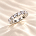 Elegant silver eternity ring featuring sparkling round-cut crystals, photographed on luxurious champagne satin fabric with soft lighting – Marla Jewellery.