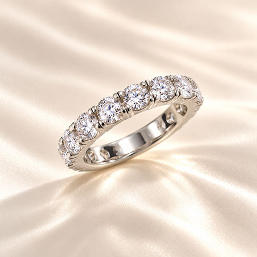 Elegant silver eternity ring featuring sparkling round-cut crystals, photographed on luxurious champagne satin fabric with soft lighting – Marla Jewellery.