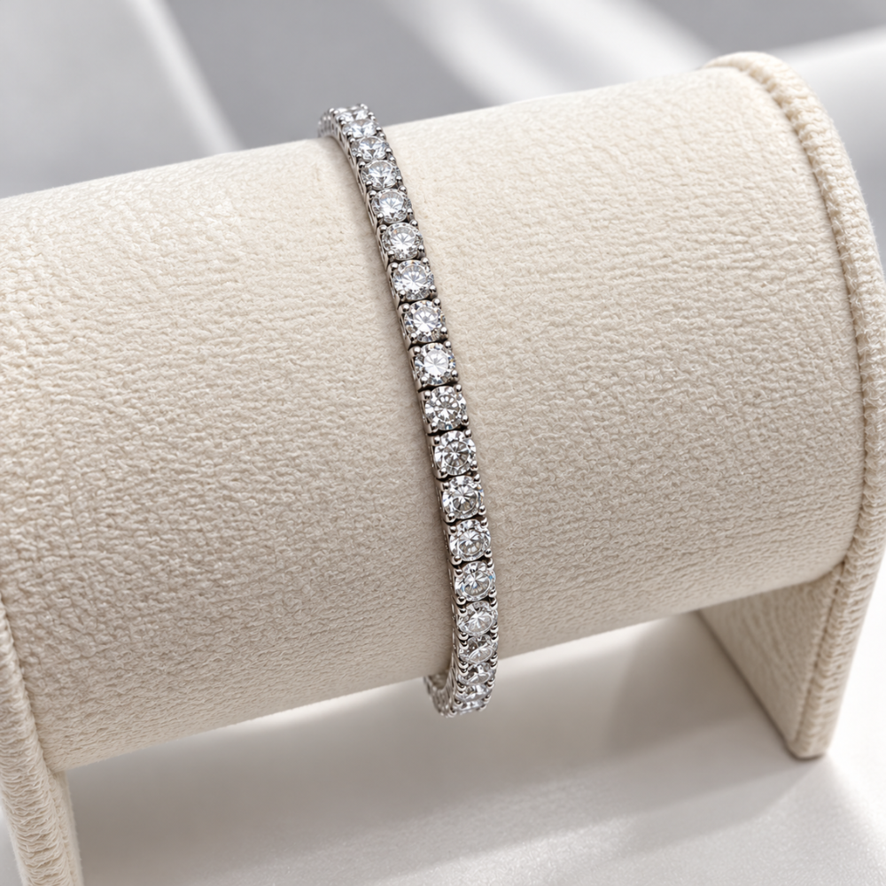 MARLA silver-tone 3mm tennis bracelet featuring brilliant round stones elegantly displayed on a cream velvet jewellery stand.