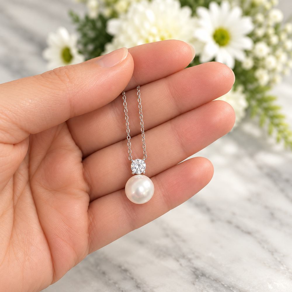 MARLA Pearl & Moissanite Pendant Necklace shown in hand with a round moissanite and white pearl drop